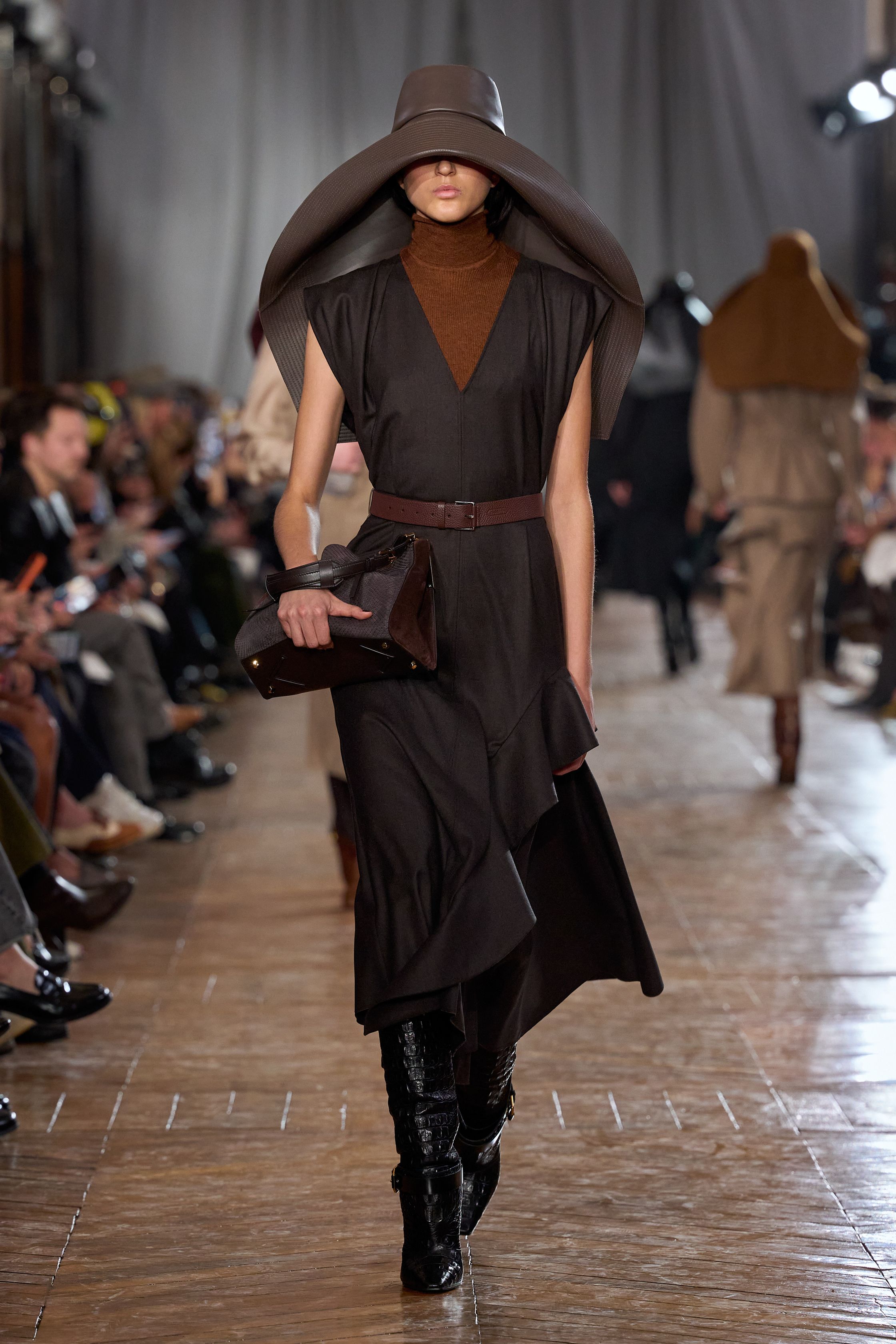Lanvin 本季回归品牌最经典的巴黎女性气质：结构精准的西装、收腰裙装、深色羊毛套装与戏剧性大檐帽形成一种冷静而克制的奢华。柔软褶皱、细腰剪裁与高靴搭配营造出带有1930年代气息的摩登贵族感，同时通过金属亮片与垂坠流苏礼服让夜晚部分显得华丽而锋利。整场秀像一场巴黎旧贵族的时装电影，优雅却不失力量-顽石频道趋势研究